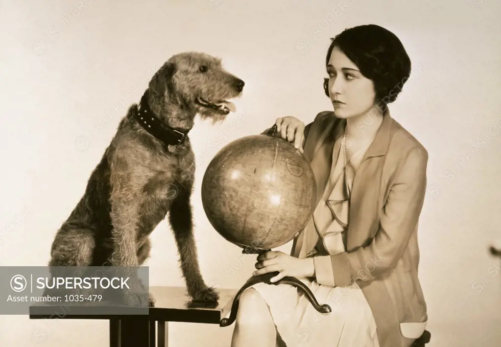 Young woman sitting with a dog holding a globe