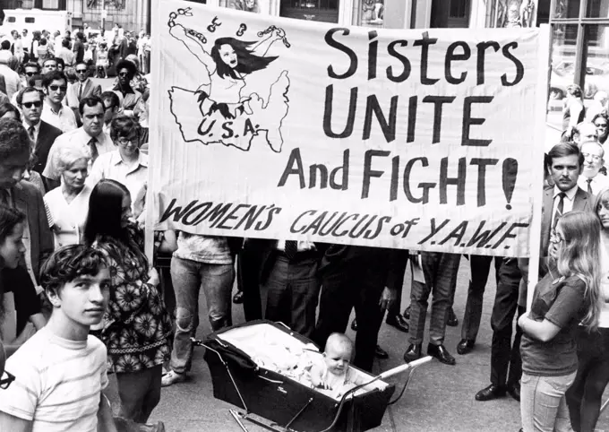 Chicago, Illinois:  August 26, 1970 The Women's Liberation movement mounted its strongest campaign for equal rights to date with over 4,000 persons turning out for the 50th anniversary of women's suffrage. The sign calls for The Women's Caucus of Youth Against War and Facism (YAWF) to unite and fight.