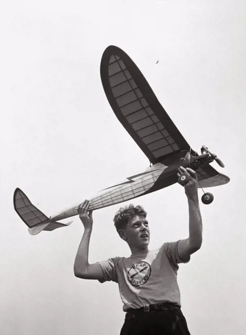 Low angle view of a teenage boy holding a airplane