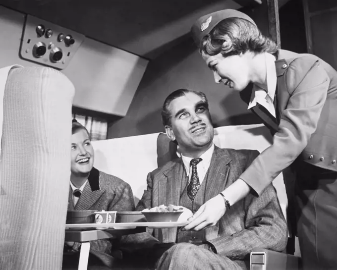 Airplane stewardess serving meals to passengers in an airplane