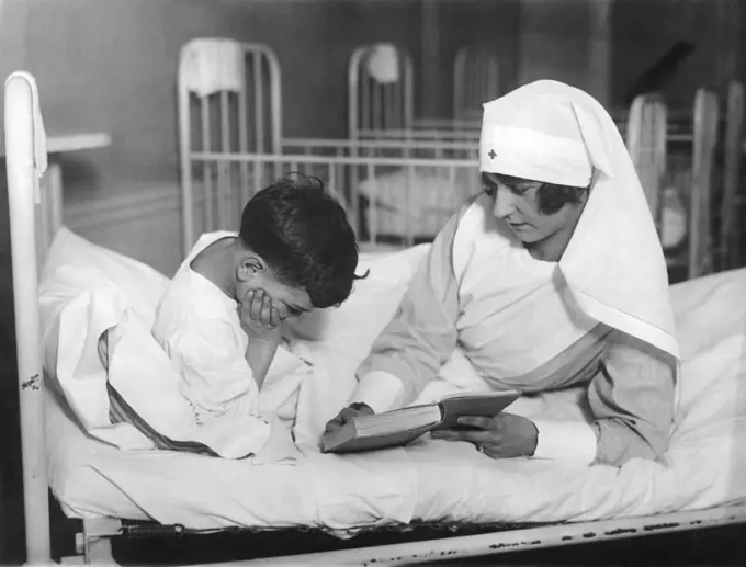 New York, New York:  January 5, 1926 New York City society girls are spending one day a week as volunteer nurses as part of their service to humanity. Miss Betty Nixon is seeing reading to a young boy at the Tonsil Hospital in Manhattan.