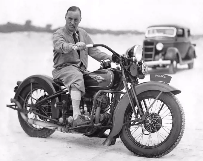 Daytona Beach, Florida:  February 13, 1935 British racer Captain Malcolm Campbell tries out a policeman's Harley Davidson, but he won't get near the 300 mph he hopes to reach in his Bluebird race car on the beach.