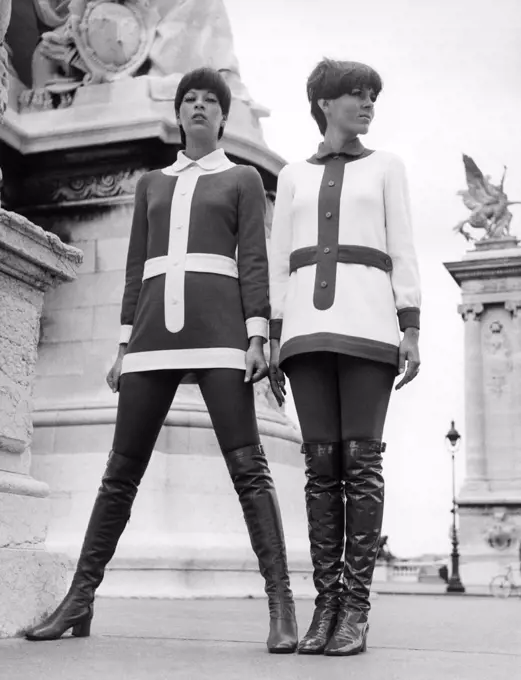 United States:   1969 Two women model inversely matching outfits and thigh high boots.
