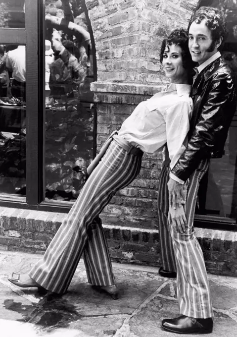 United States:   1969 A hip looking couple models matching striped bellbottom pants in a rather seductive fashion.