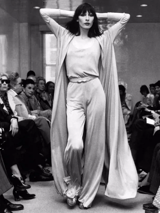 New York, New York: May 23, 1972 Angelica Huston models a Halston Originals jersey evening pants ensemble with a matching full coat.