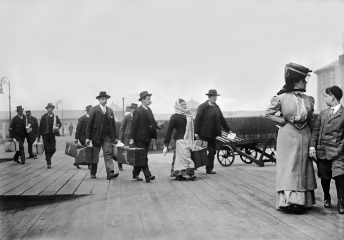 New York, New York:  c. 1895 Immigrants carrying their luggage as they arrivive at Ellis Island in NY harbor.