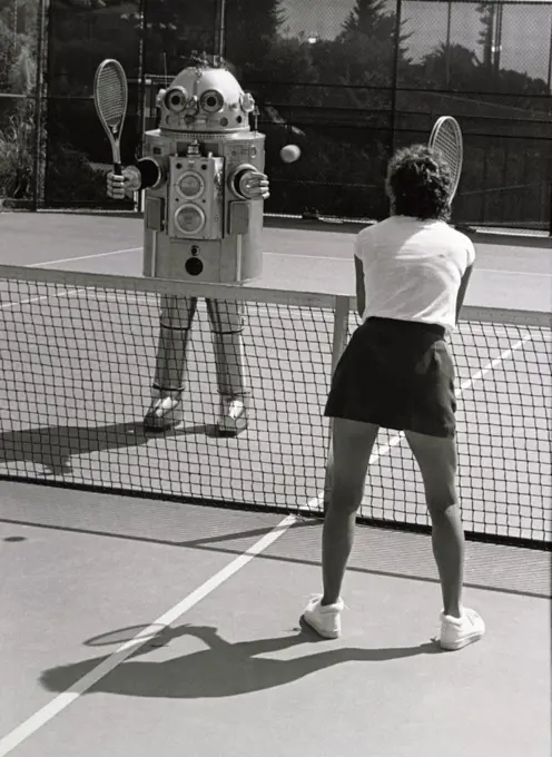 Rear view of a woman playing tennis with a robot