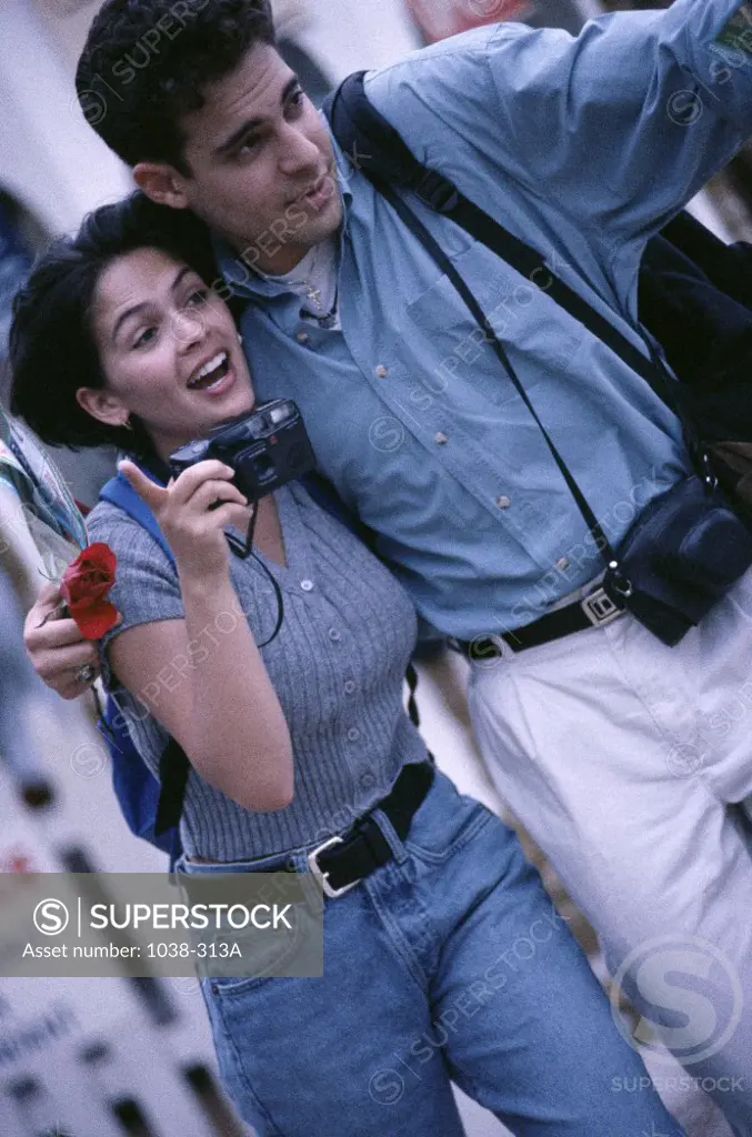 Young couple holding a camera looking ahead