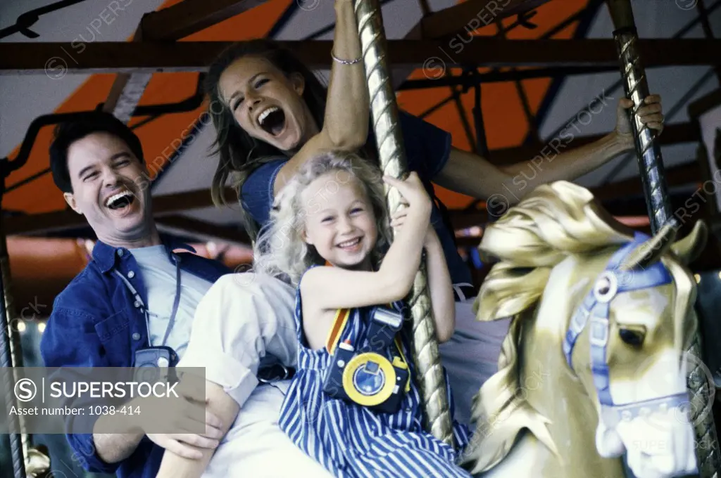 Portrait of parents with their daughter riding a carousel horse