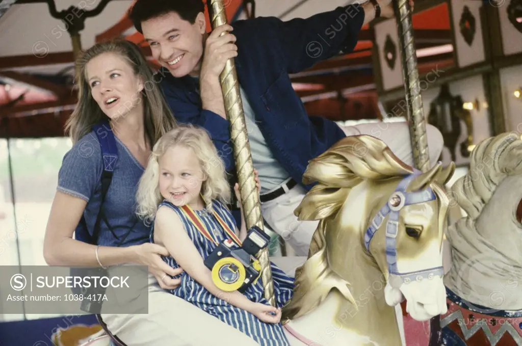 Parents with their daughter riding a carousel horse
