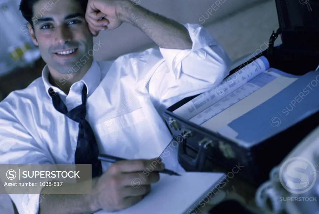 Portrait of a young businessman writing on paper
