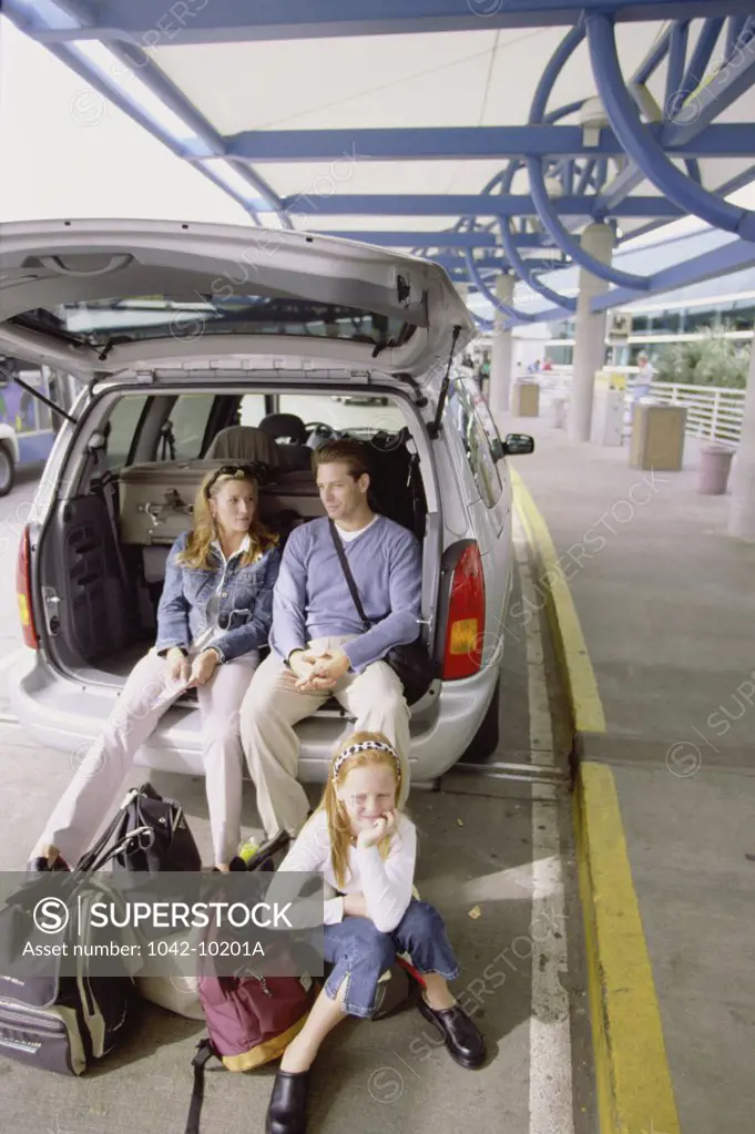 Parents and their daughter sitting at the back of a car