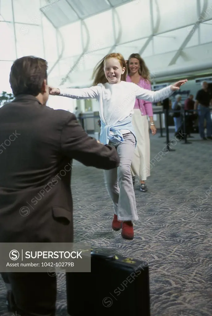 Girl running to hug her father in an airport