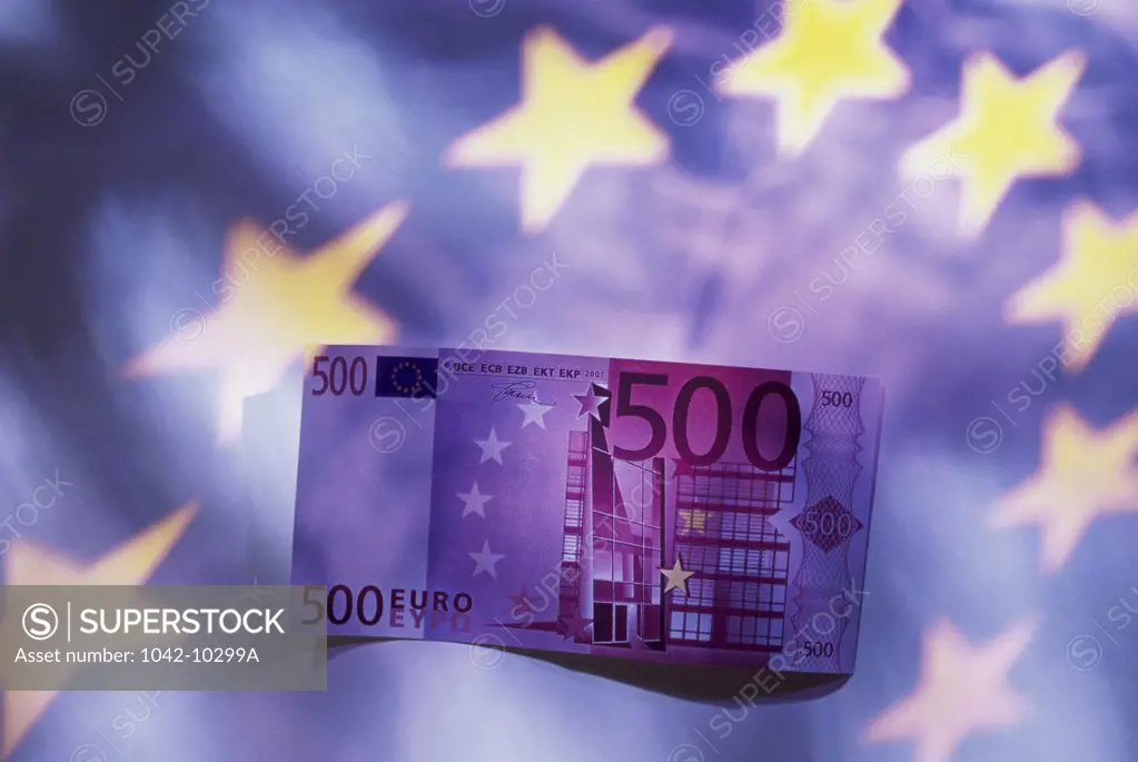 Close-up of a euro banknote with the European Union flag in the background