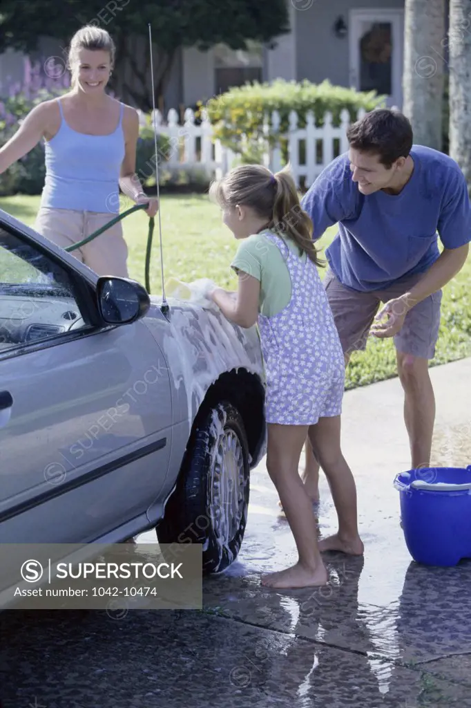 Parents washing the car with their daughter