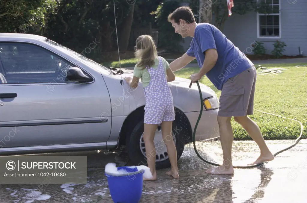 Father washing his car with his daughter