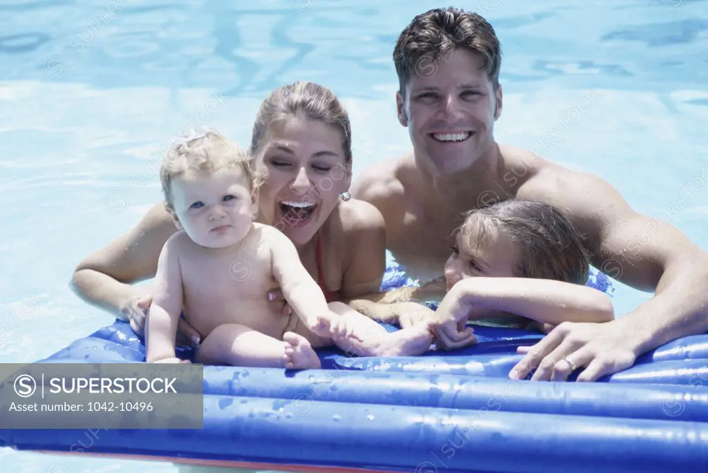Portrait of a young couple on a pool raft with their two daughters