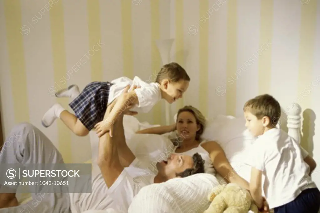 Parents playing with their sons in a bed