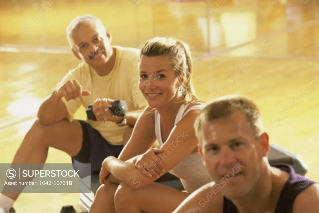 Portrait of two men and a woman in a gym