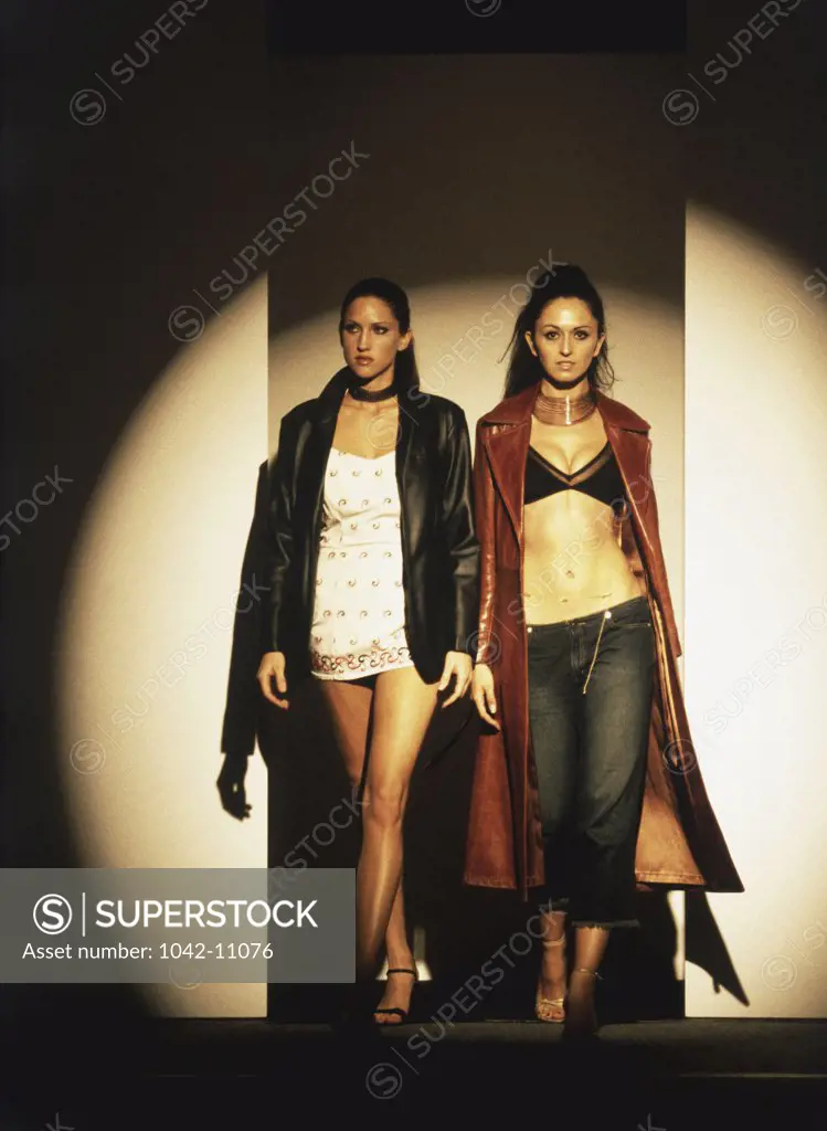 Two female fashion models standing on a catwalk