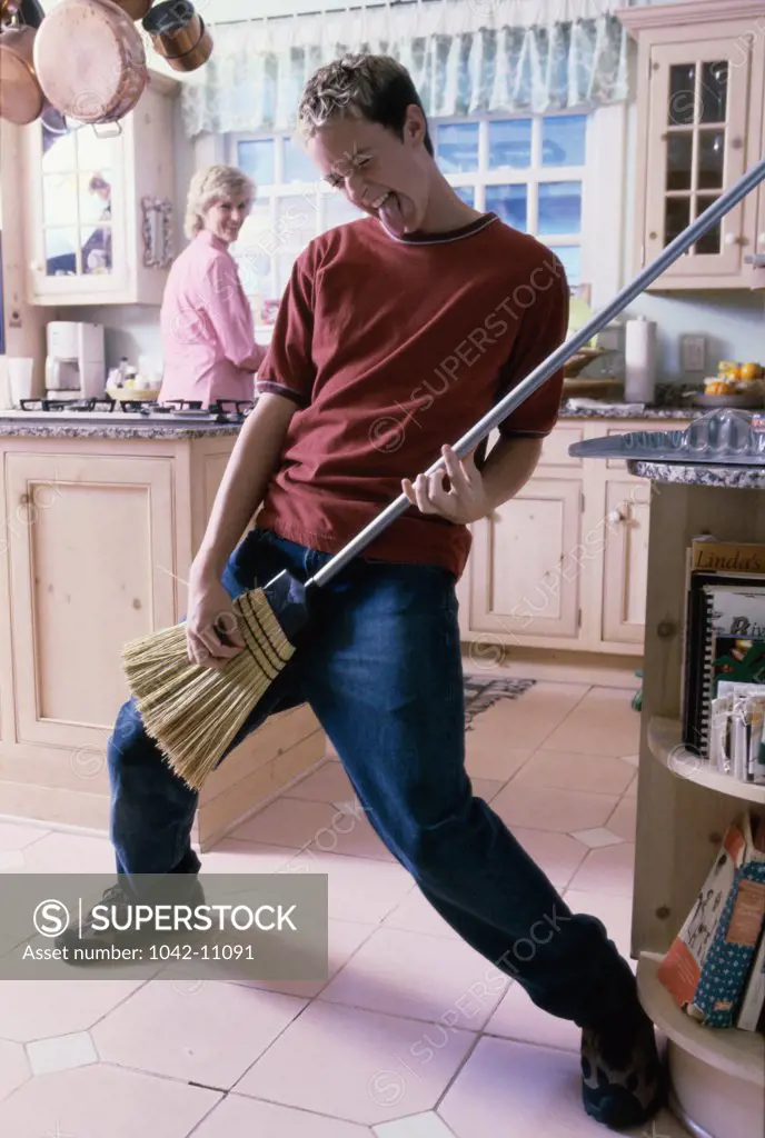 Young man pretending to play a guitar with a broom