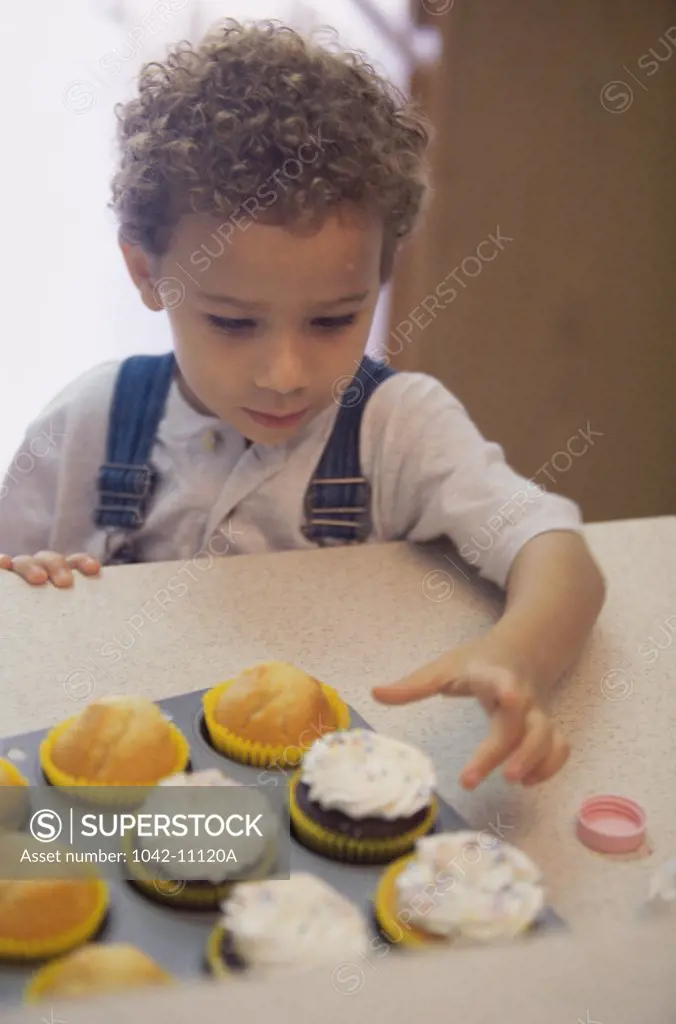 Boy taking a cupcake from a tray