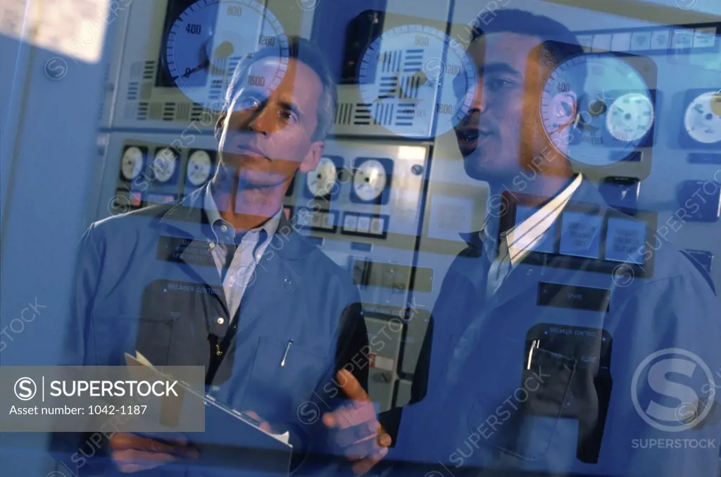 Reflection of two mid adult men on a control panel