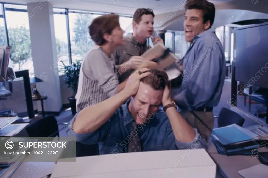 Three businessmen and a businesswoman shouting in an office