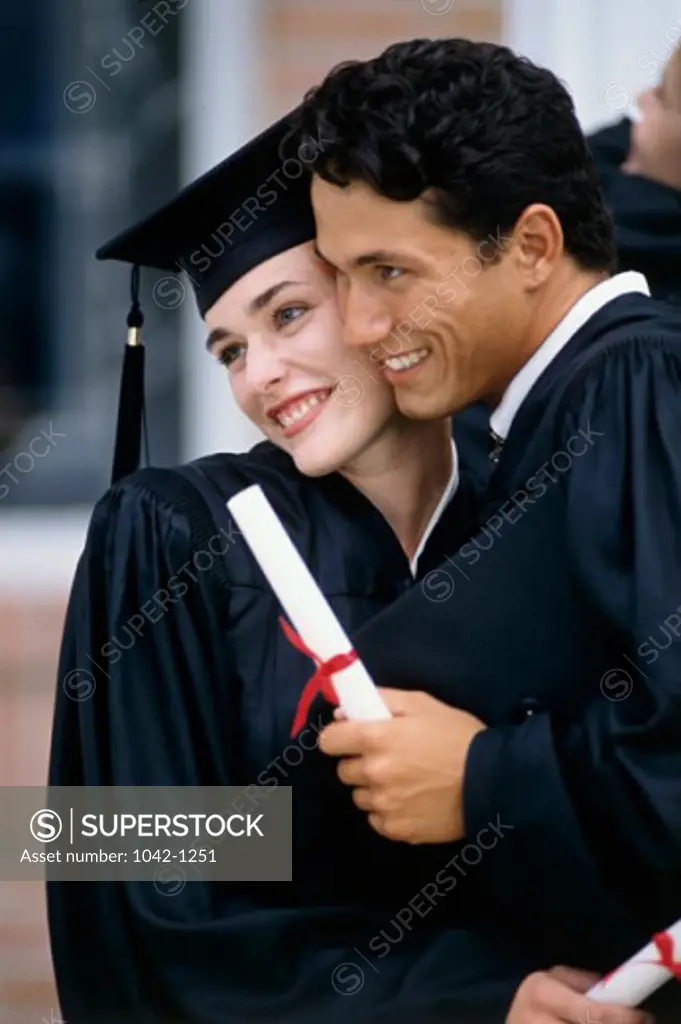 Young male graduate hugging a young female graduate