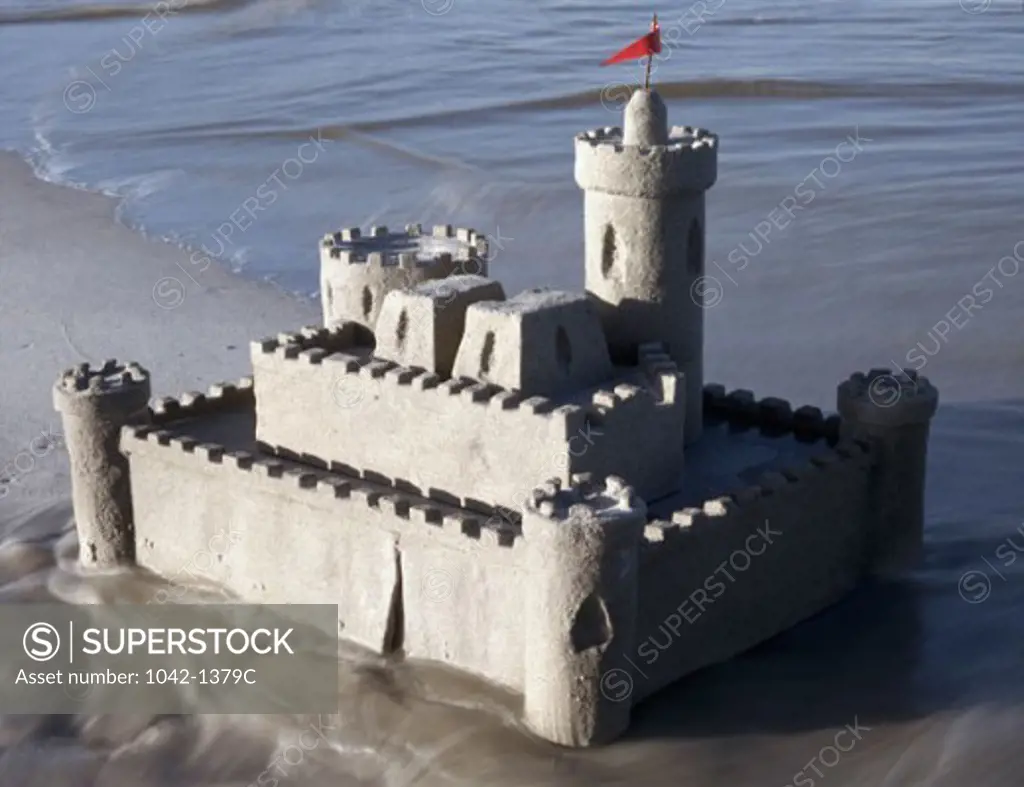 Sandcastle on the beach with a red flag