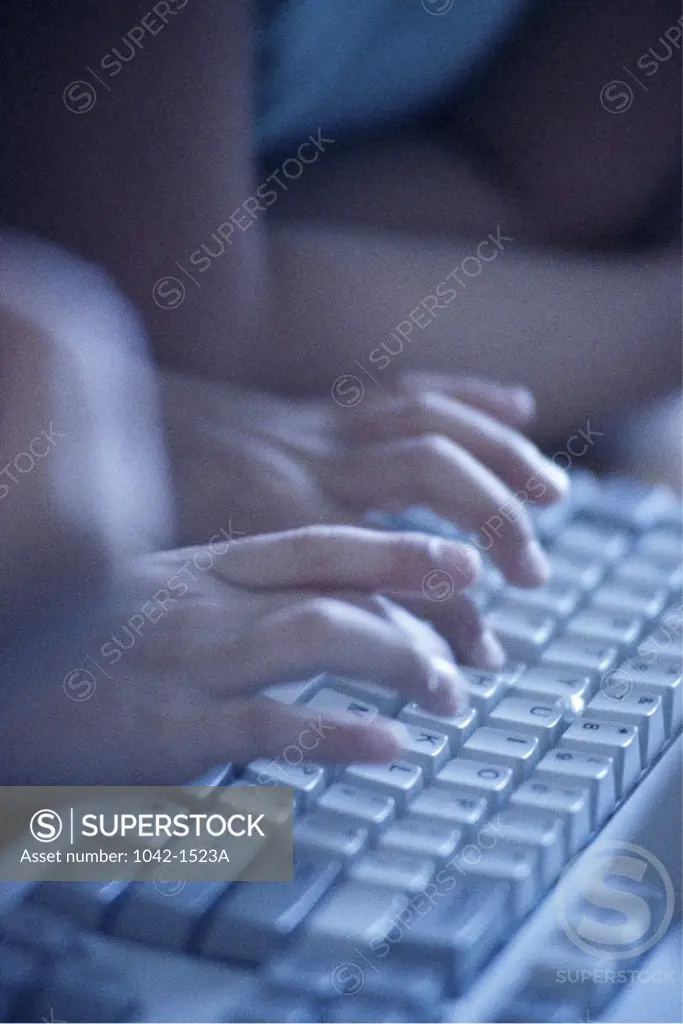 Close-up of a child's hand typing on a computer keyboard