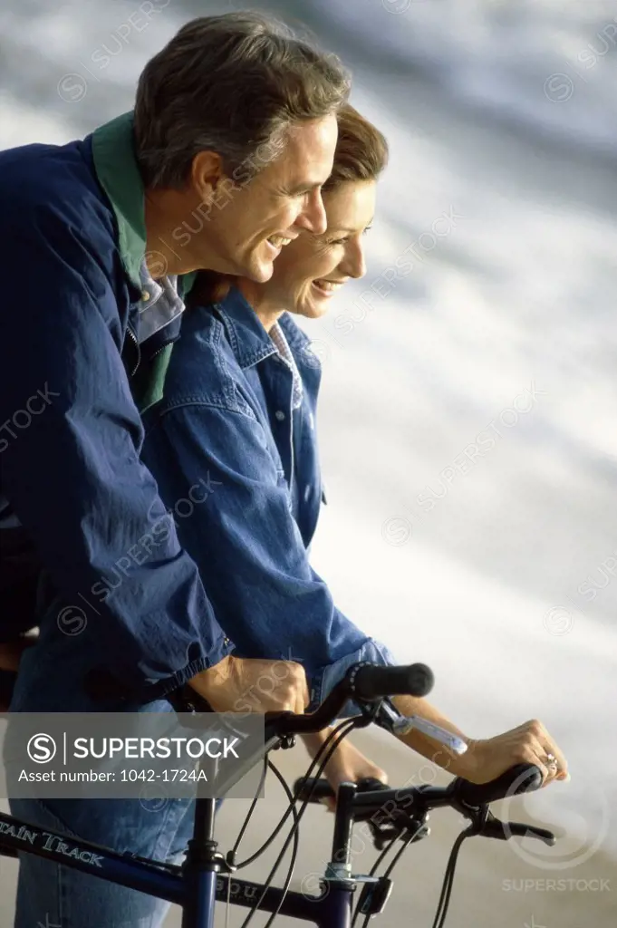 Mature couple holding bicycles on the beach