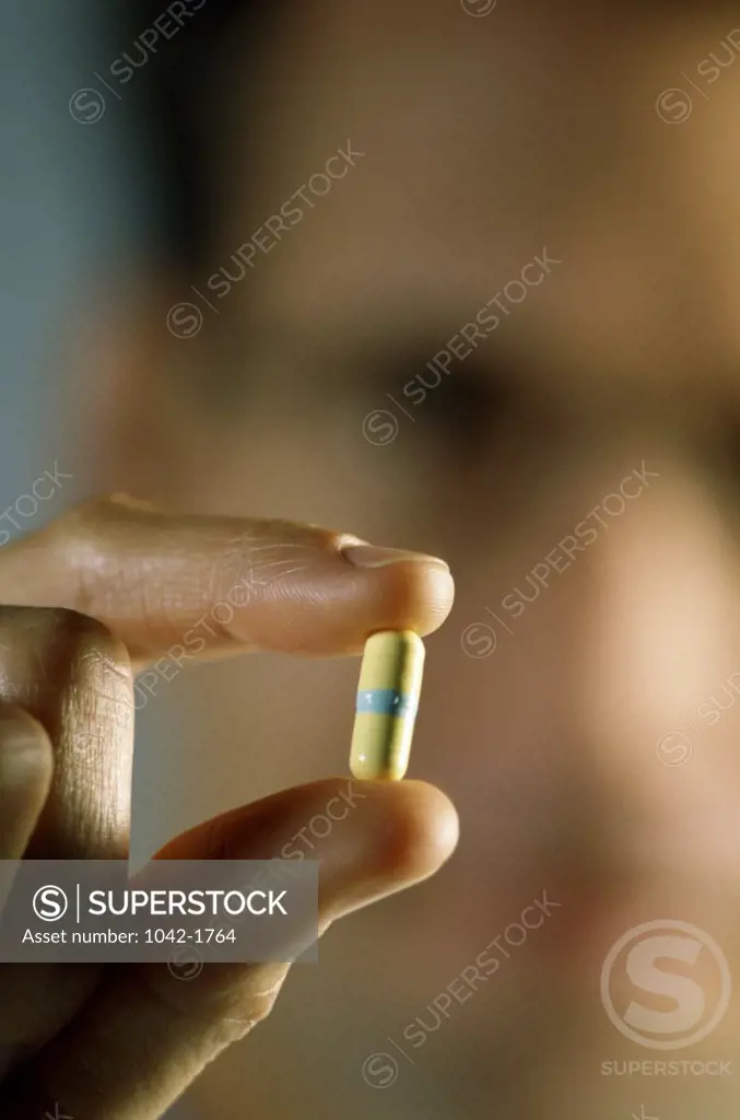 Close-up of a person's hand holding a capsule