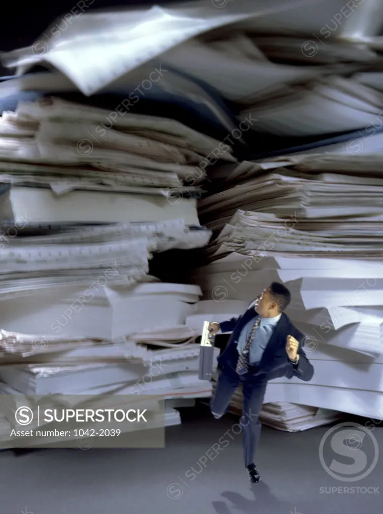 Businessman running from a stack of papers