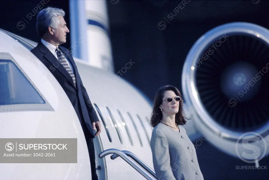 Businessman and a businesswoman climbing down a staircase of an airplane