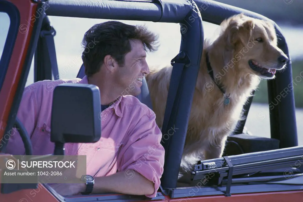 Mid adult man and his dog in a jeep