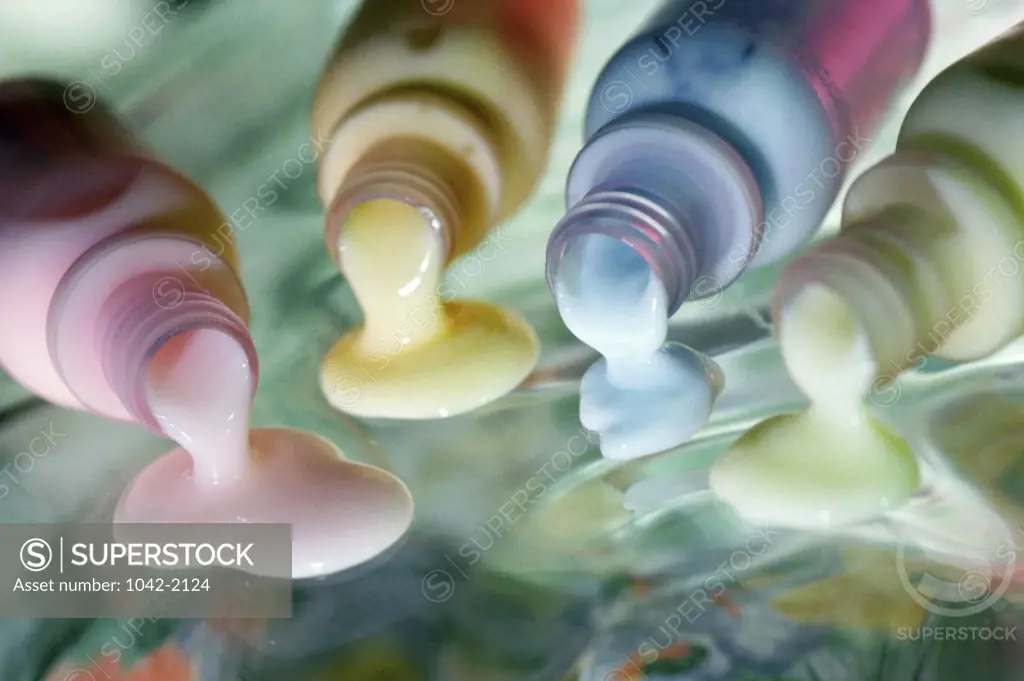 Close-up of different colored lotion spilling out from bottles