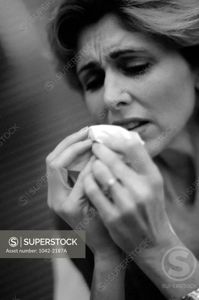 Close-up of a mid adult woman sneezing into a handkerchief