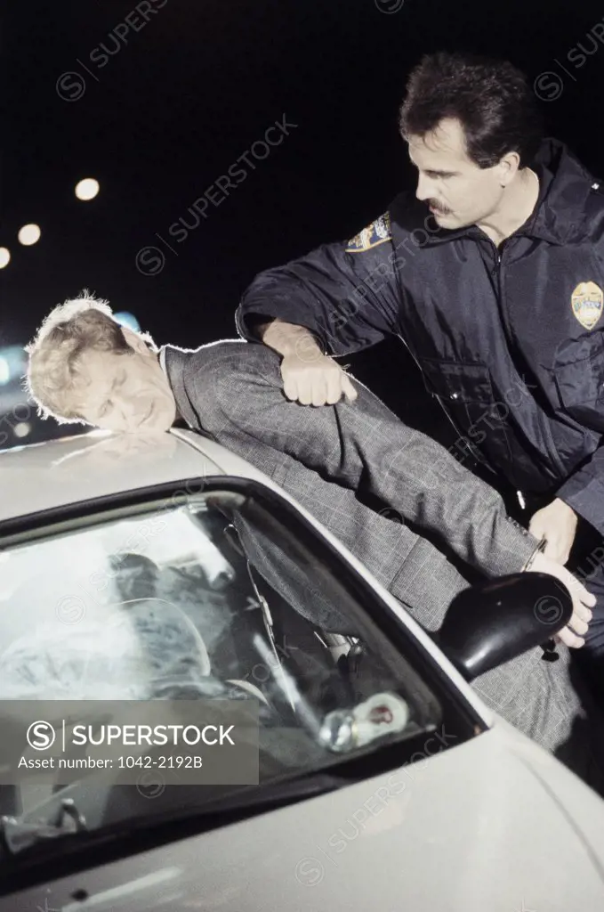 Side profile of a mid adult man being arrested by a police officer