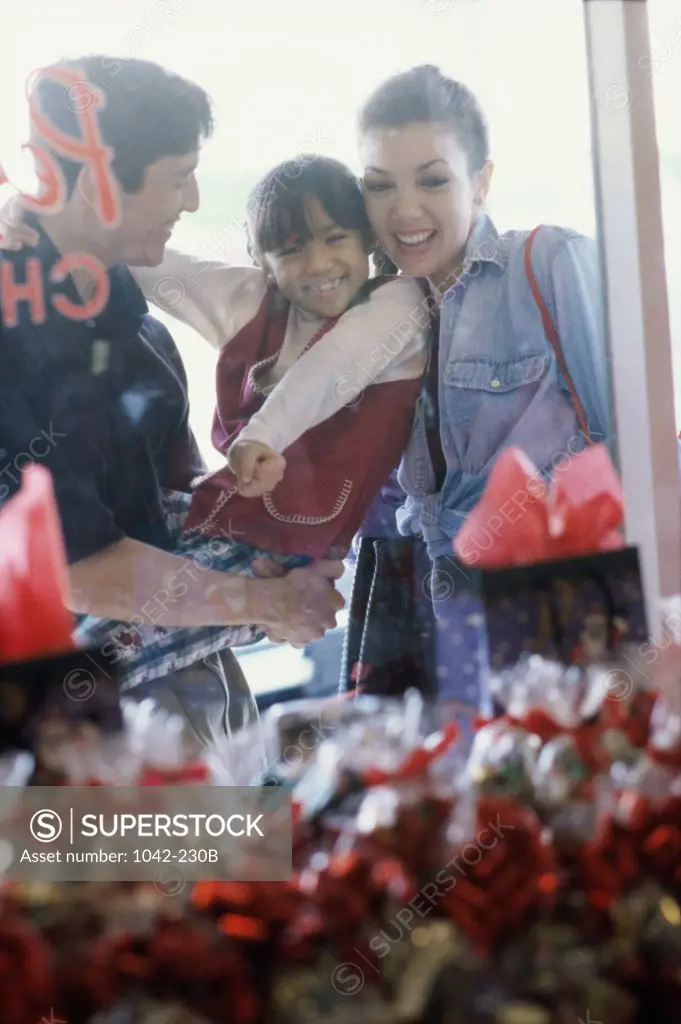 Parents with their daughter looking at the window display of a store