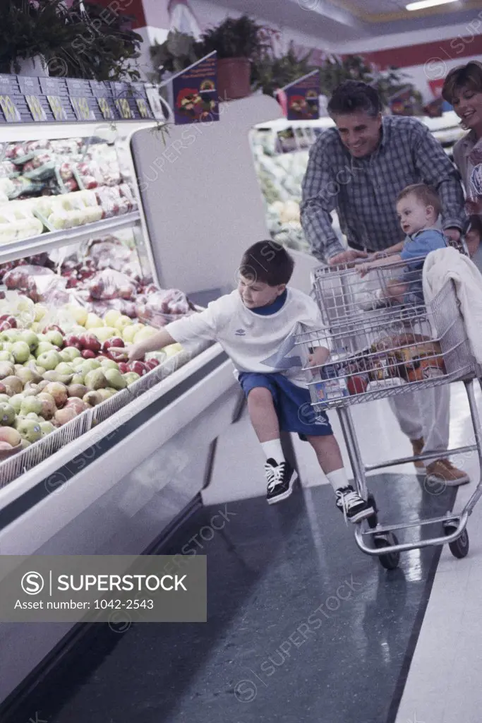 Mid adult couple with their children pushing a shopping cart in a supermarket