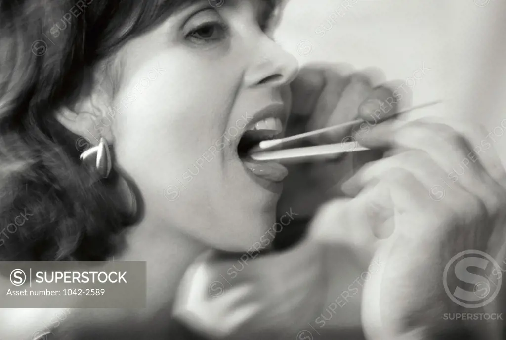 Close-up of a person taking a saliva sample with a cotton swab from a young woman