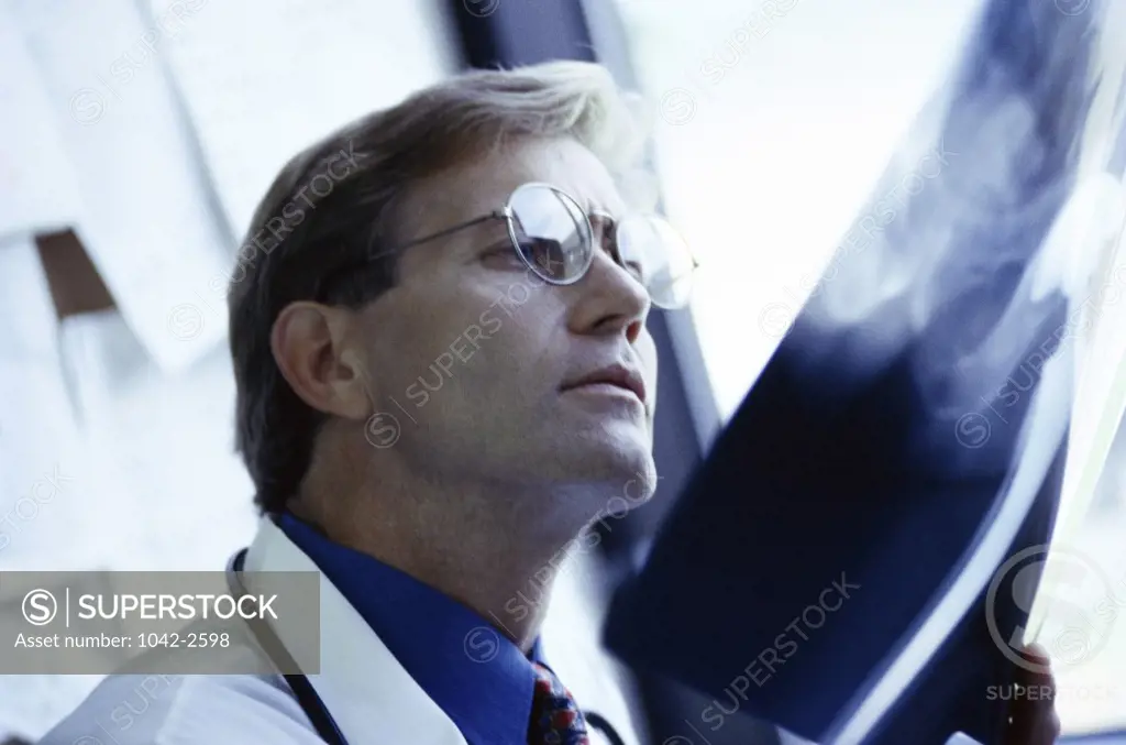 Side profile of a male doctor examining an x-ray report