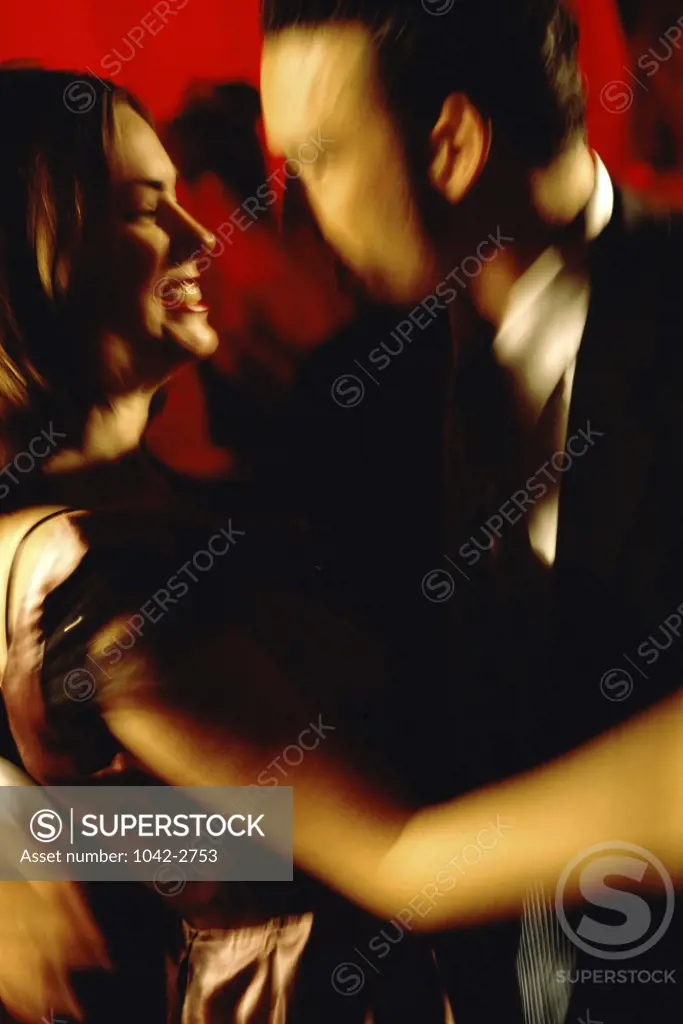 Side profile of a young couple dancing in a nightclub