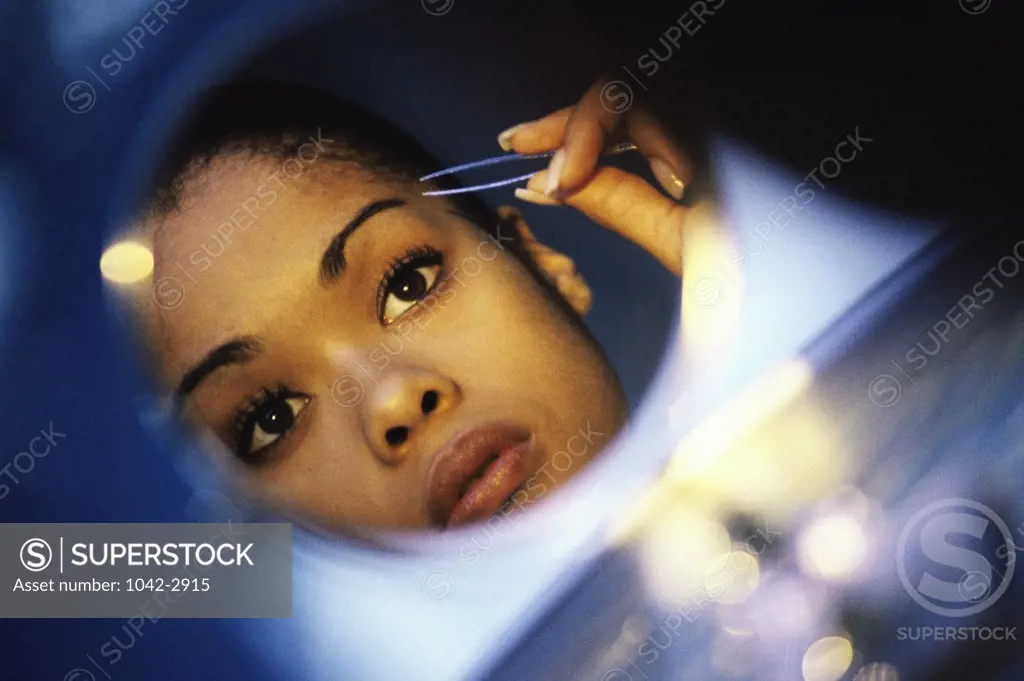 Young woman tweezing her eyebrows
