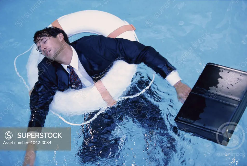 Businessman floating on a life belt