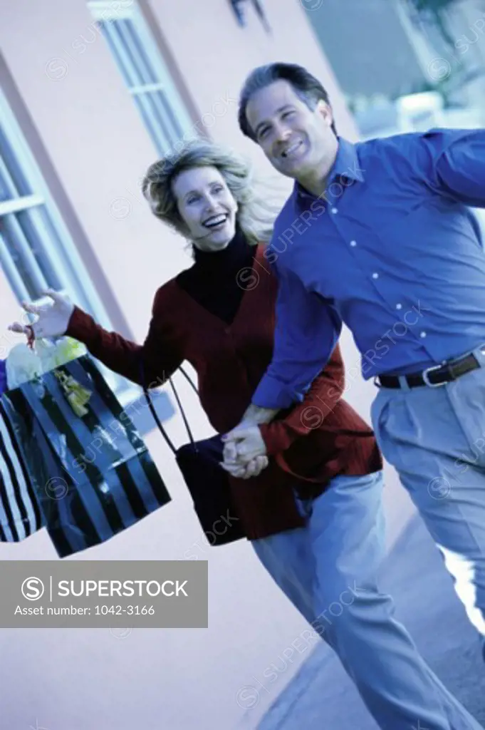 Mature couple running with shopping bags