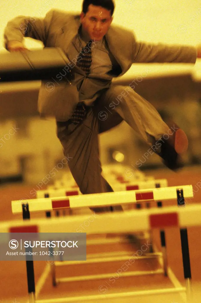 Businessman jumping over hurdles