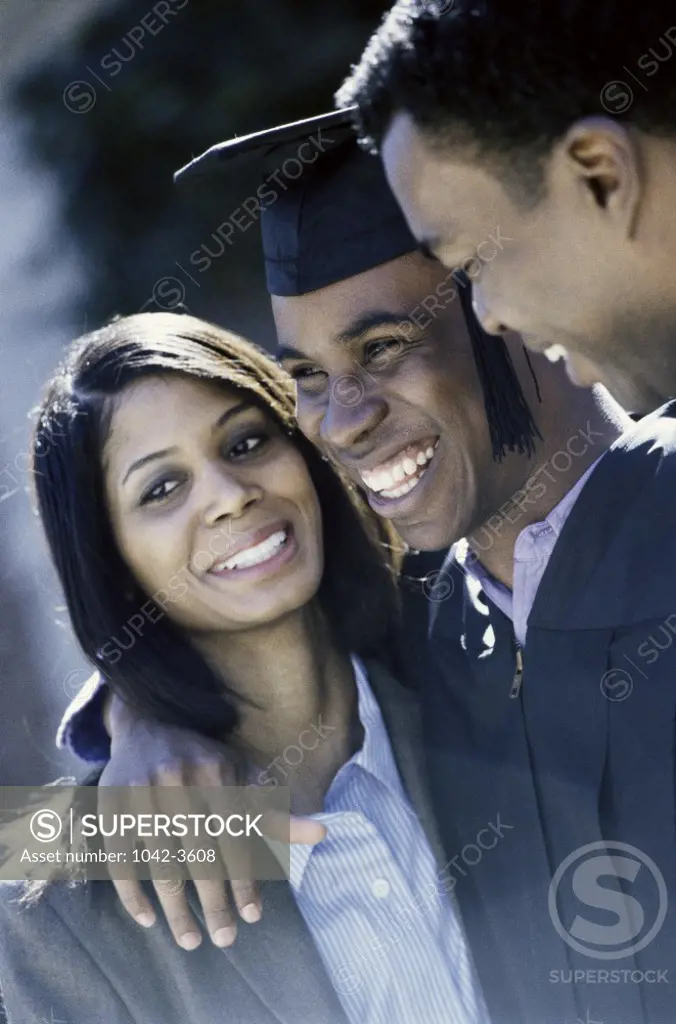 Young male graduate standing with his parents