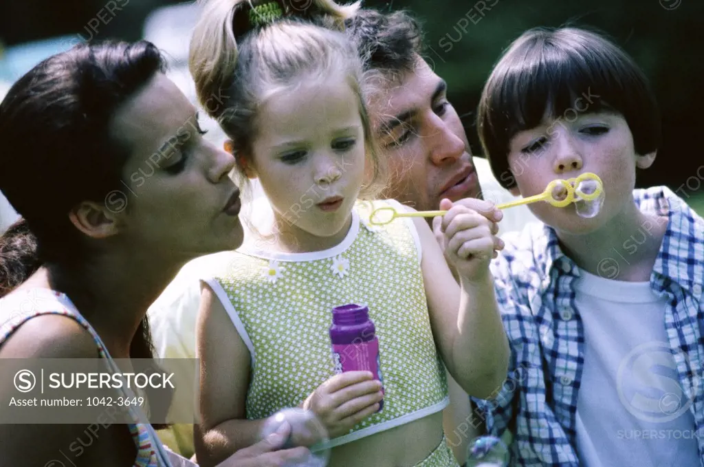Parents with their son and daughter playing with soap bubbles